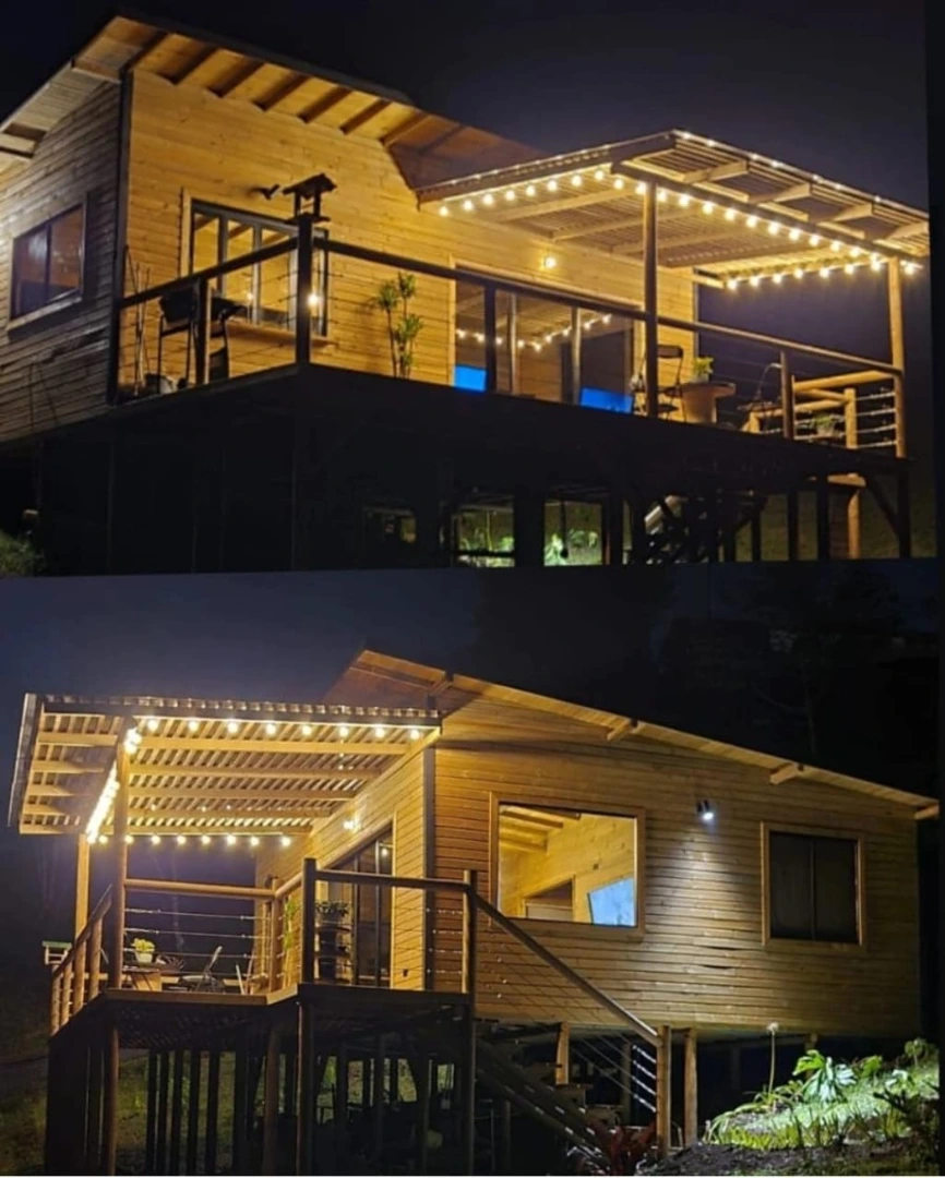 Cabaña campestre en madera inmunizada iluminada de noche en El Retiro, Antioquia – Constructora La Guadalupana